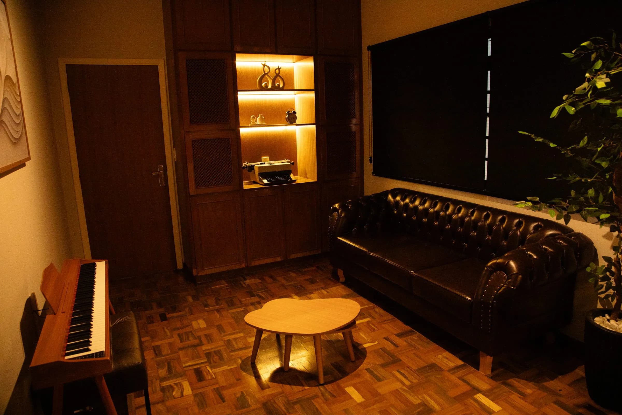 Lounge do escritório, com sofá chesterfield e piano